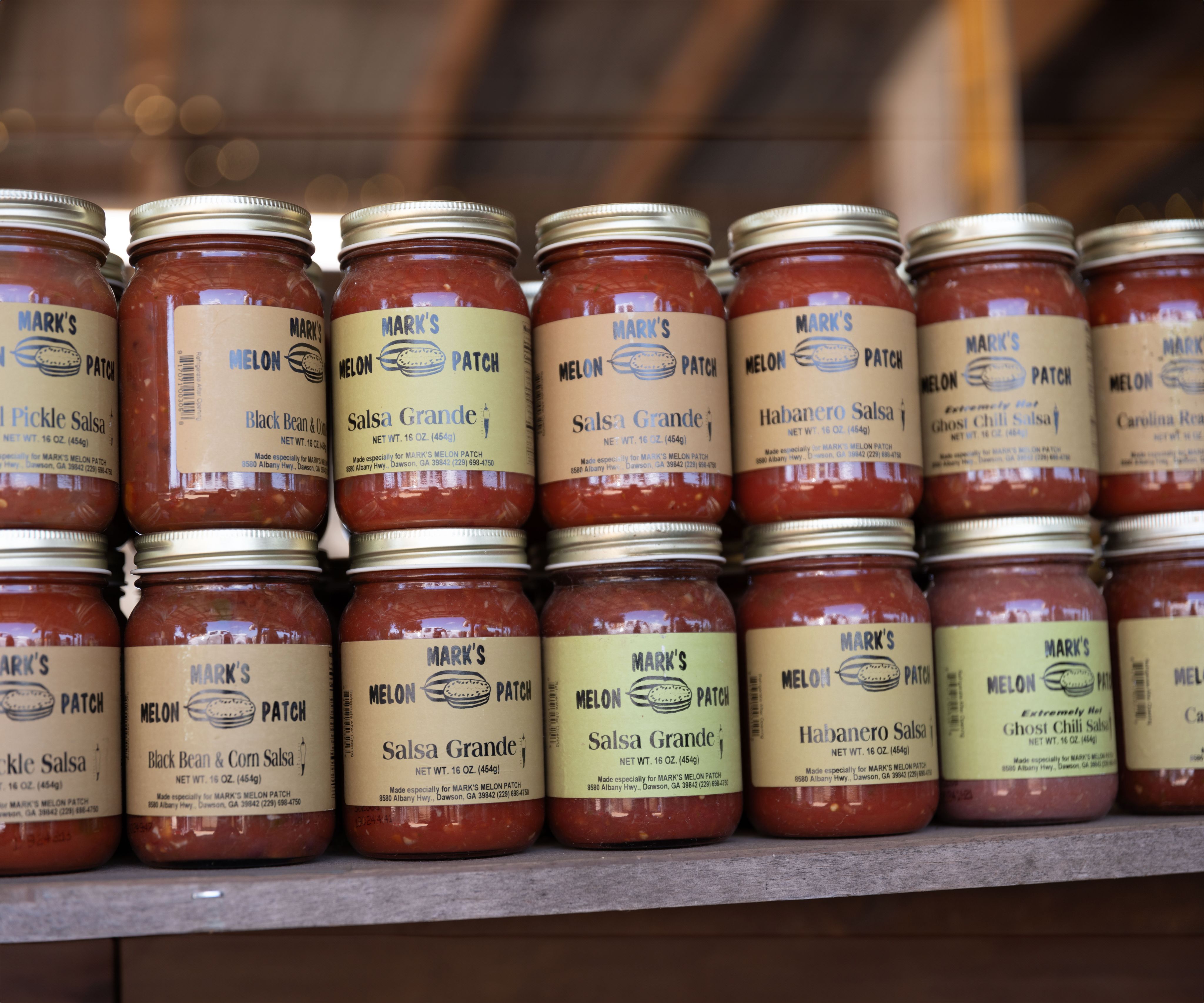 Two rows of stacked salsa jars with beige colored Mark's Melon Patch labels on display.