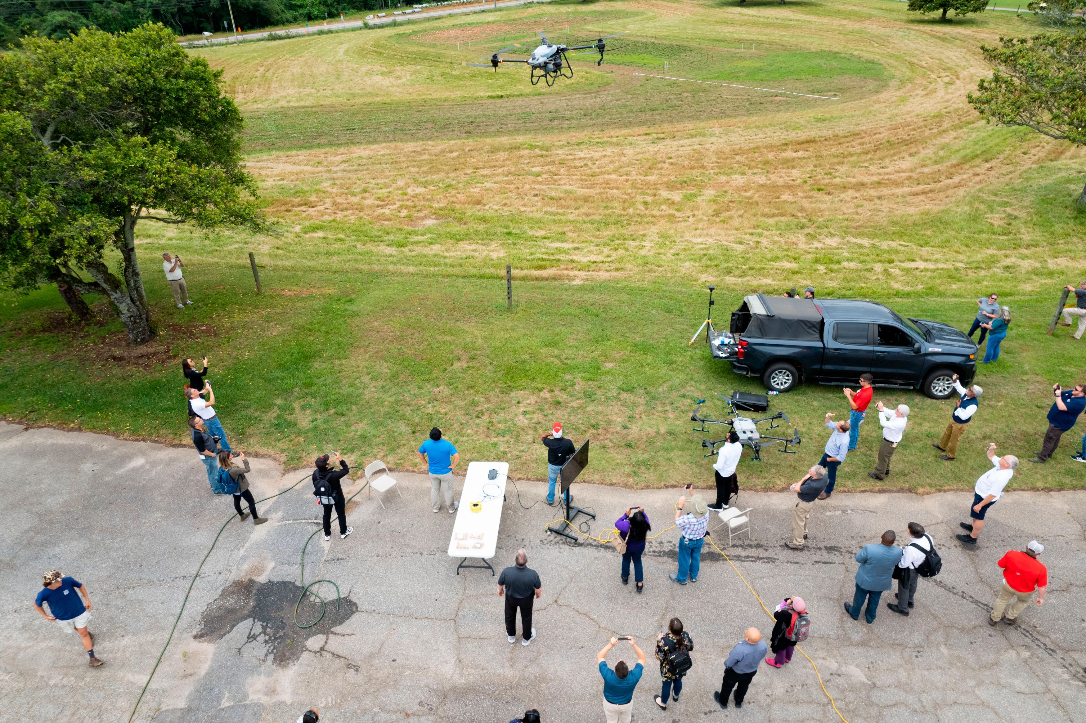 Assistant Professor and Extension Precision Ag Specialist Simer Virk, black shirt blue jeans, talks about the uses of a sprayer drone during a demonstration as part of the Institute for Integrated Precision Agriculture Conference.