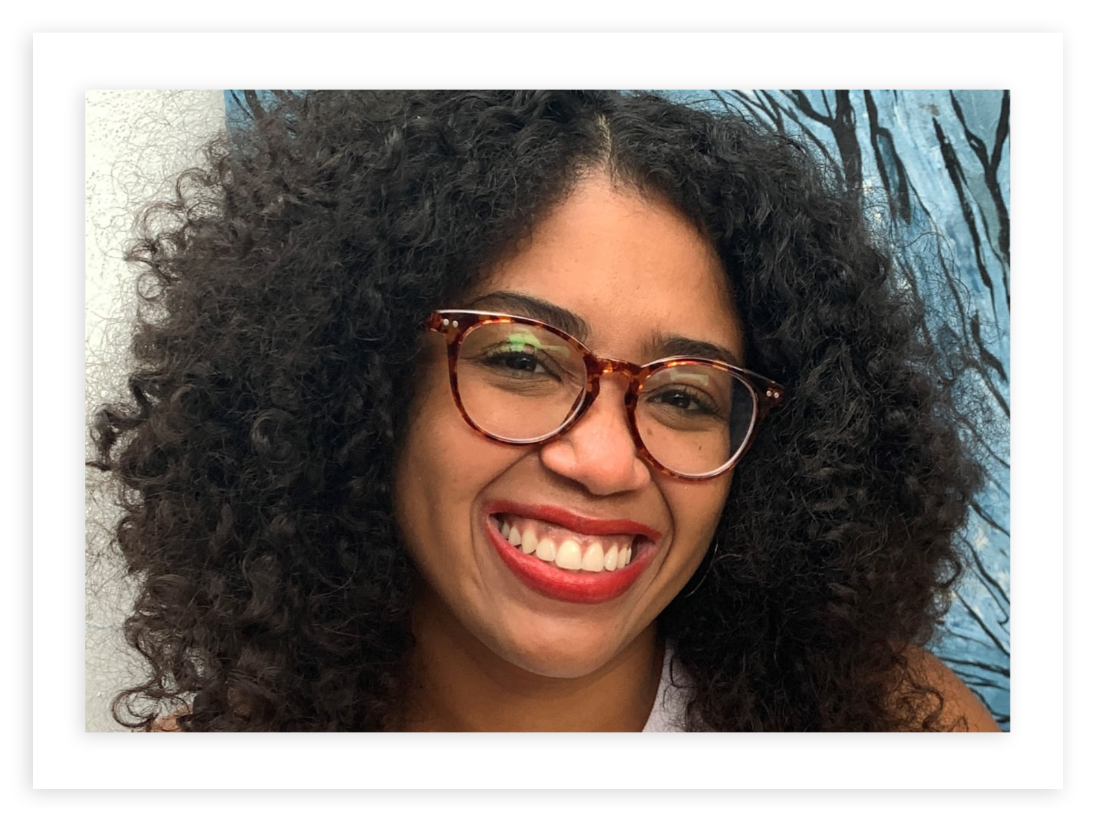 Anna Williams, wearing tortoiseshell glasses and red lipstick, smiles broadly