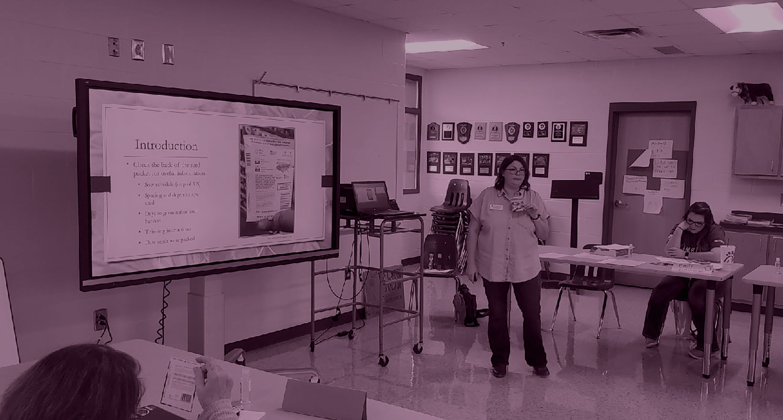 Agent stands at presentation in front of middle school class to teach a lesson in agriculture.