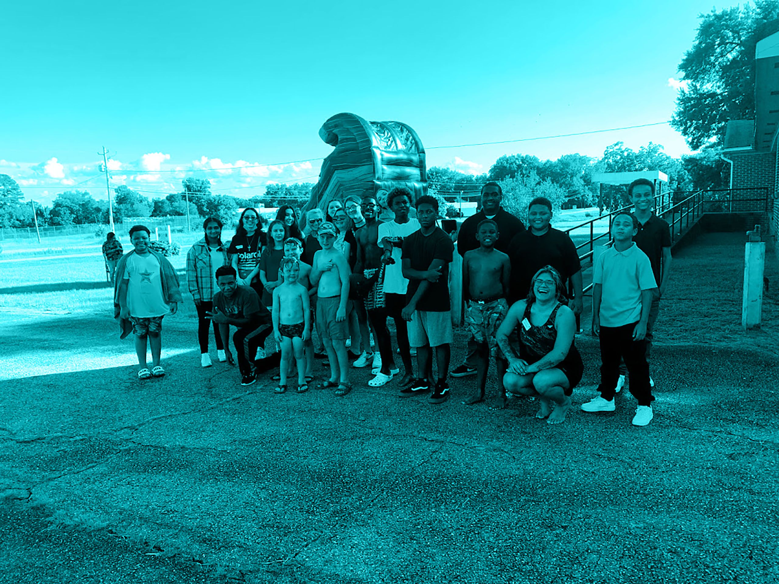 Cheerful, diverse group of youth outside in front of a bouncy house.