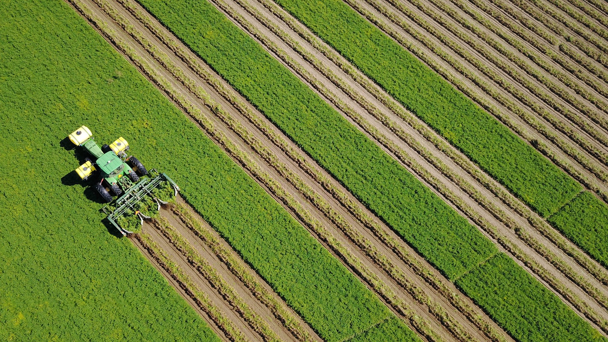 Ariel of industrial tractor plowing field diagonally.