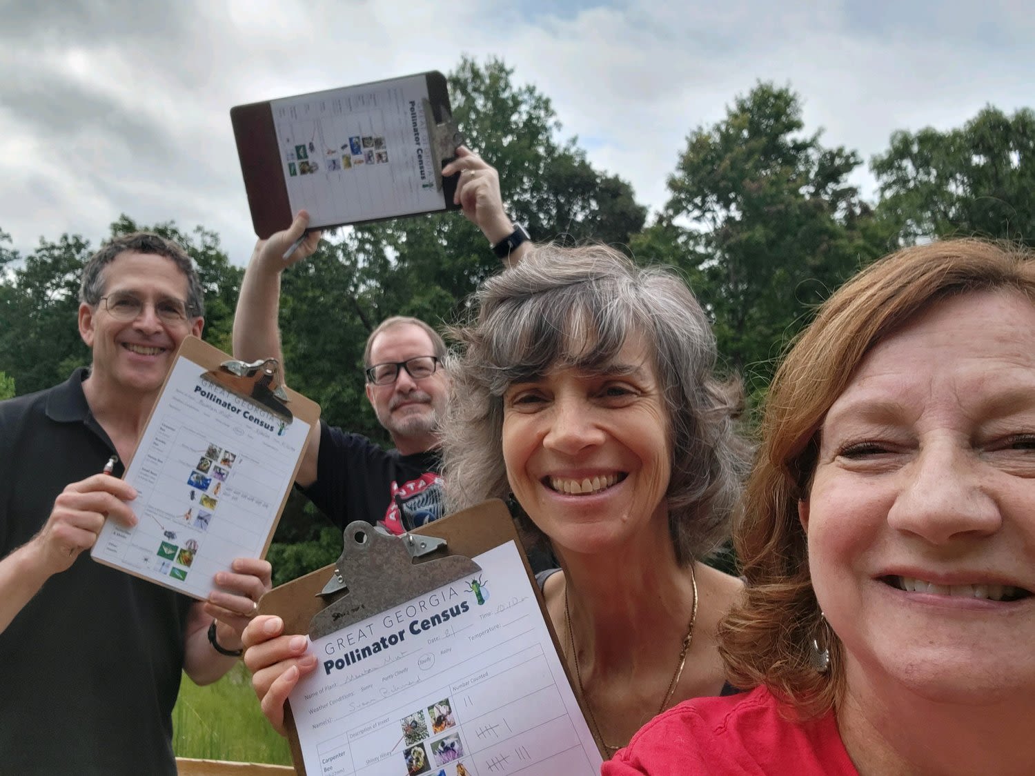 Four smiling people hold clipboards with their completed pollinator census assessments.
