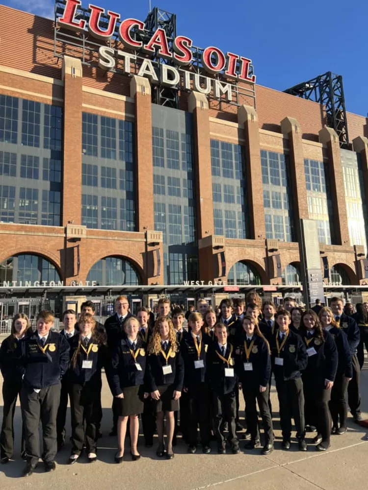 FFA students in uniform gather in front of the Lucas Oil Stadium with the sun on their faces