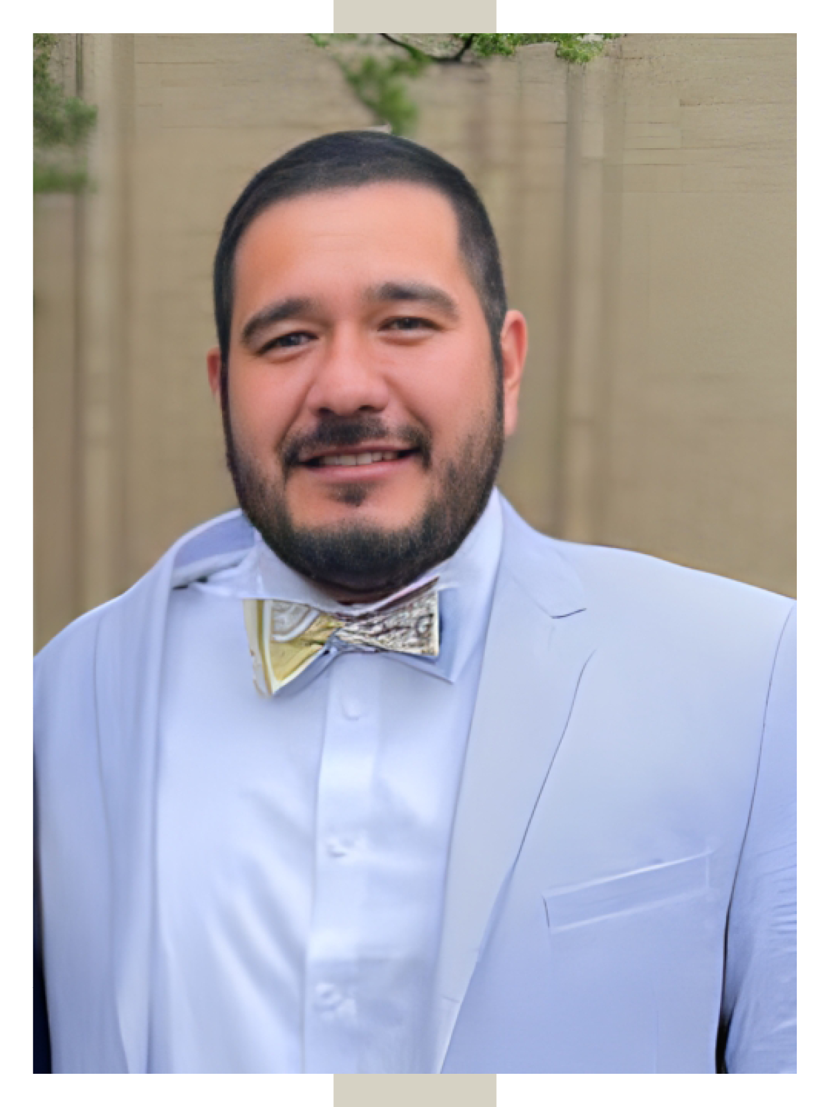 Felipe Pedraza smiles in a light blue suit and patterned bow tie