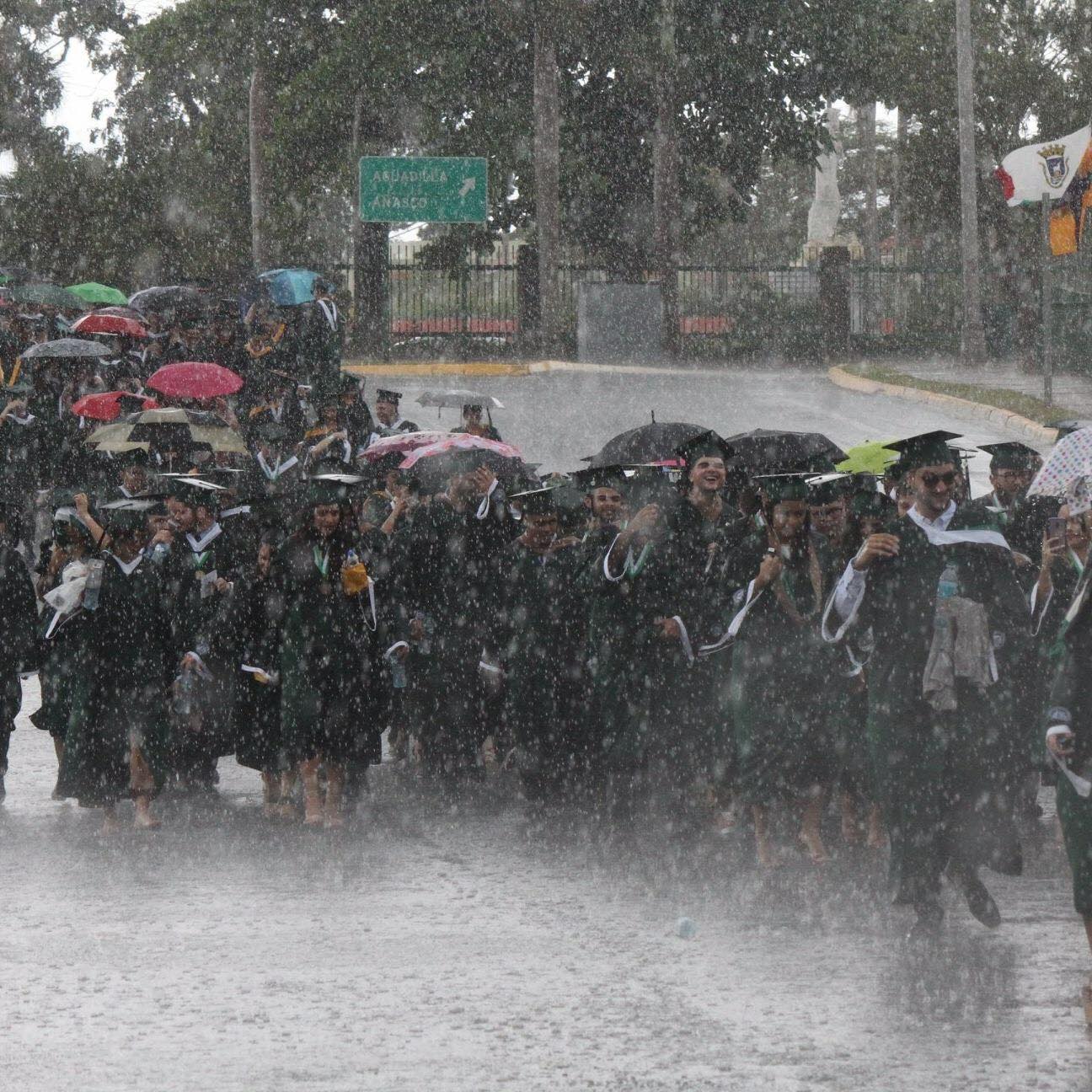 University of Puerto Rico-Mayaguez graduates are caught in the rain, with many smiling and laughing