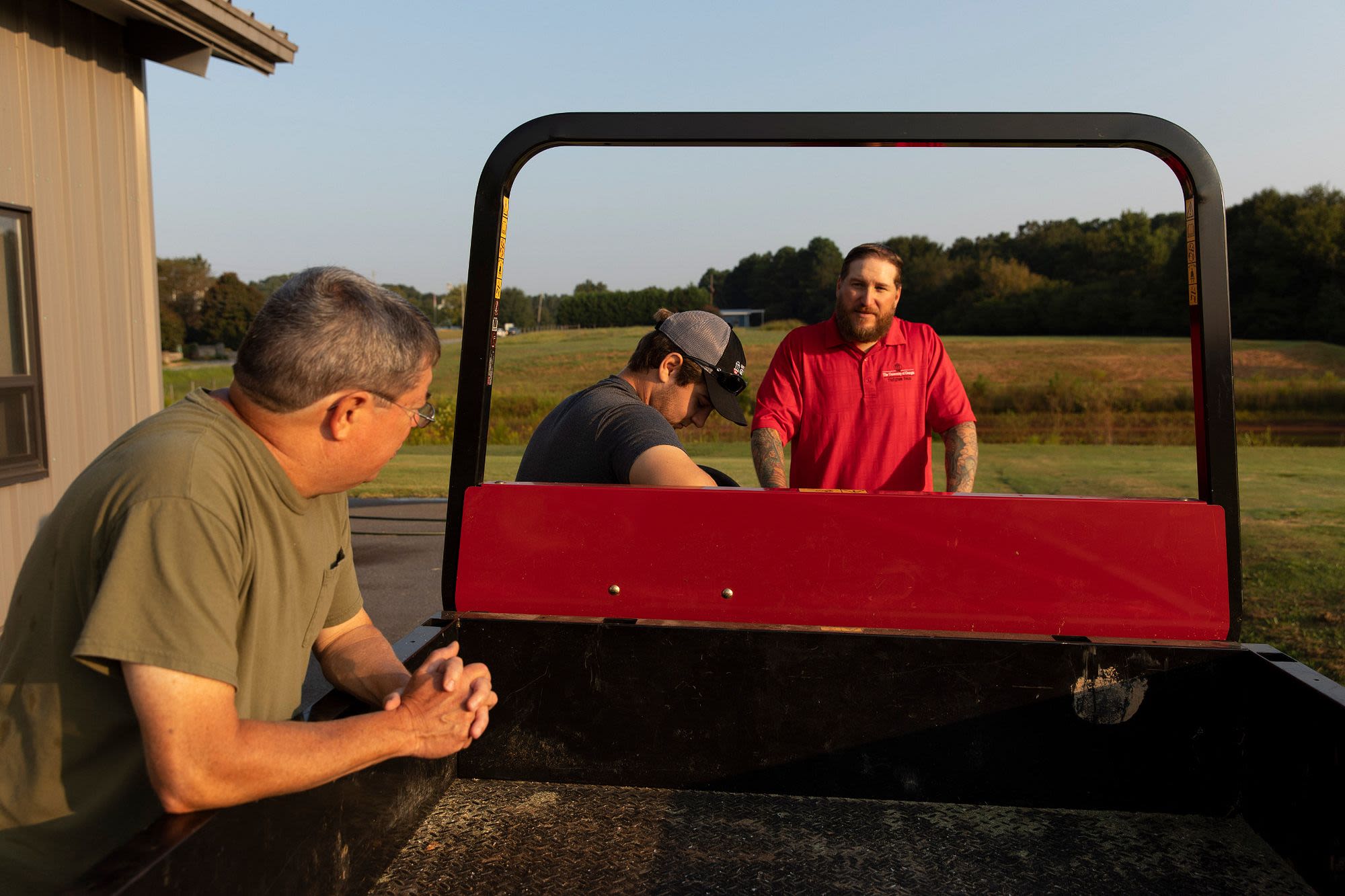 Three men discuss while standing around a vehicle at the Athens Turfgrass Research and Education Center