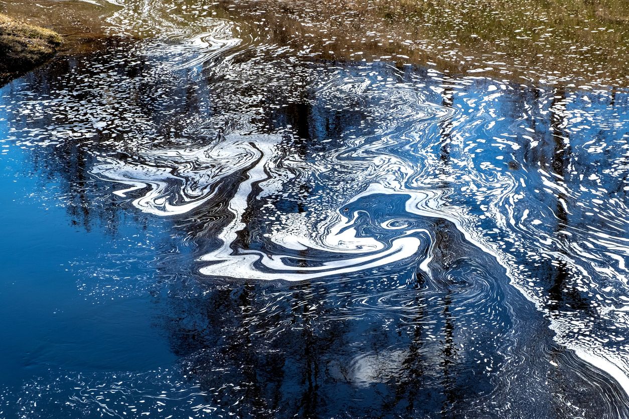 Swirling foam on top of polluted body of water.