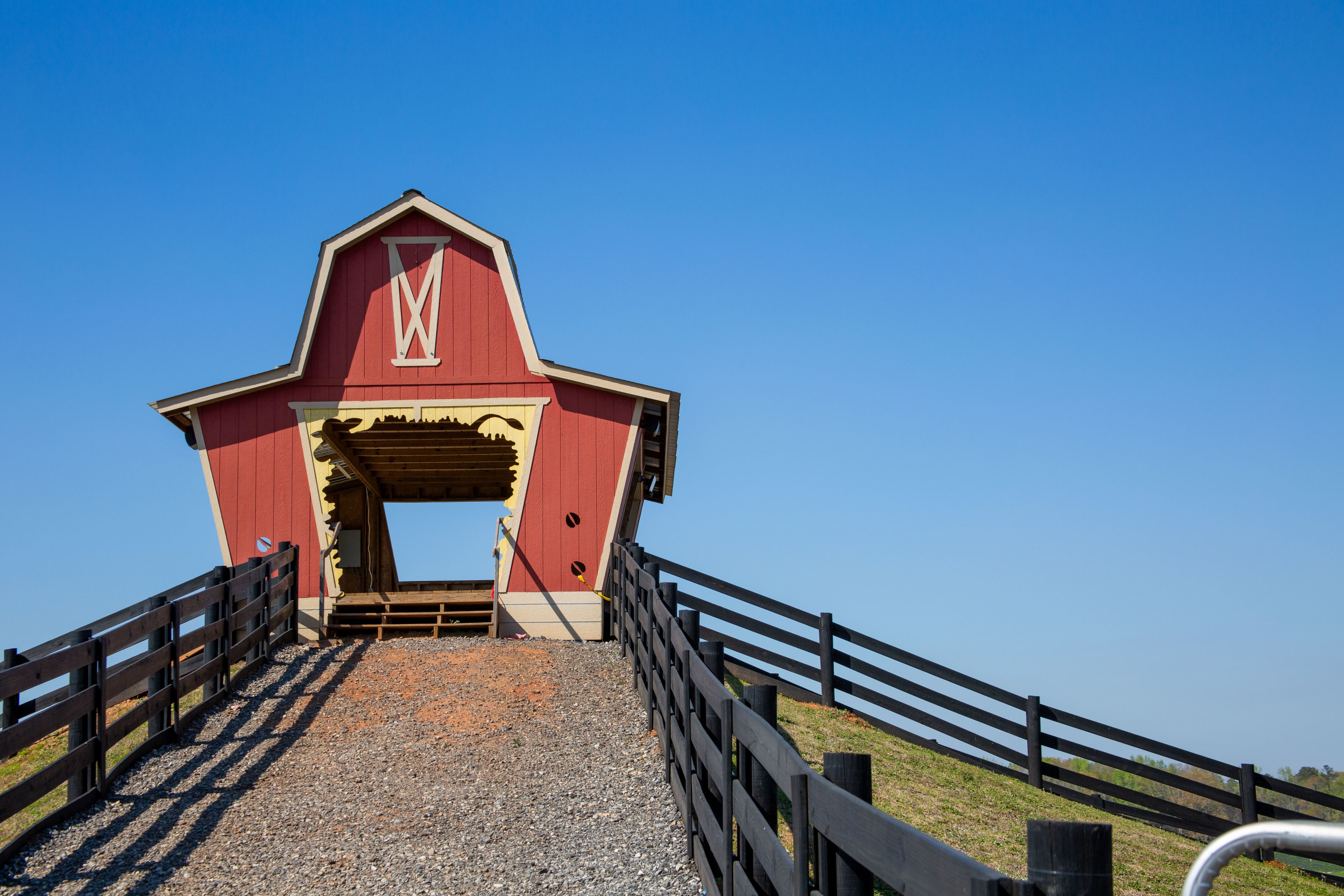 A small archway with the facade of a red barn atop a hill, this is part of an attraction at Southern Belle Farms.