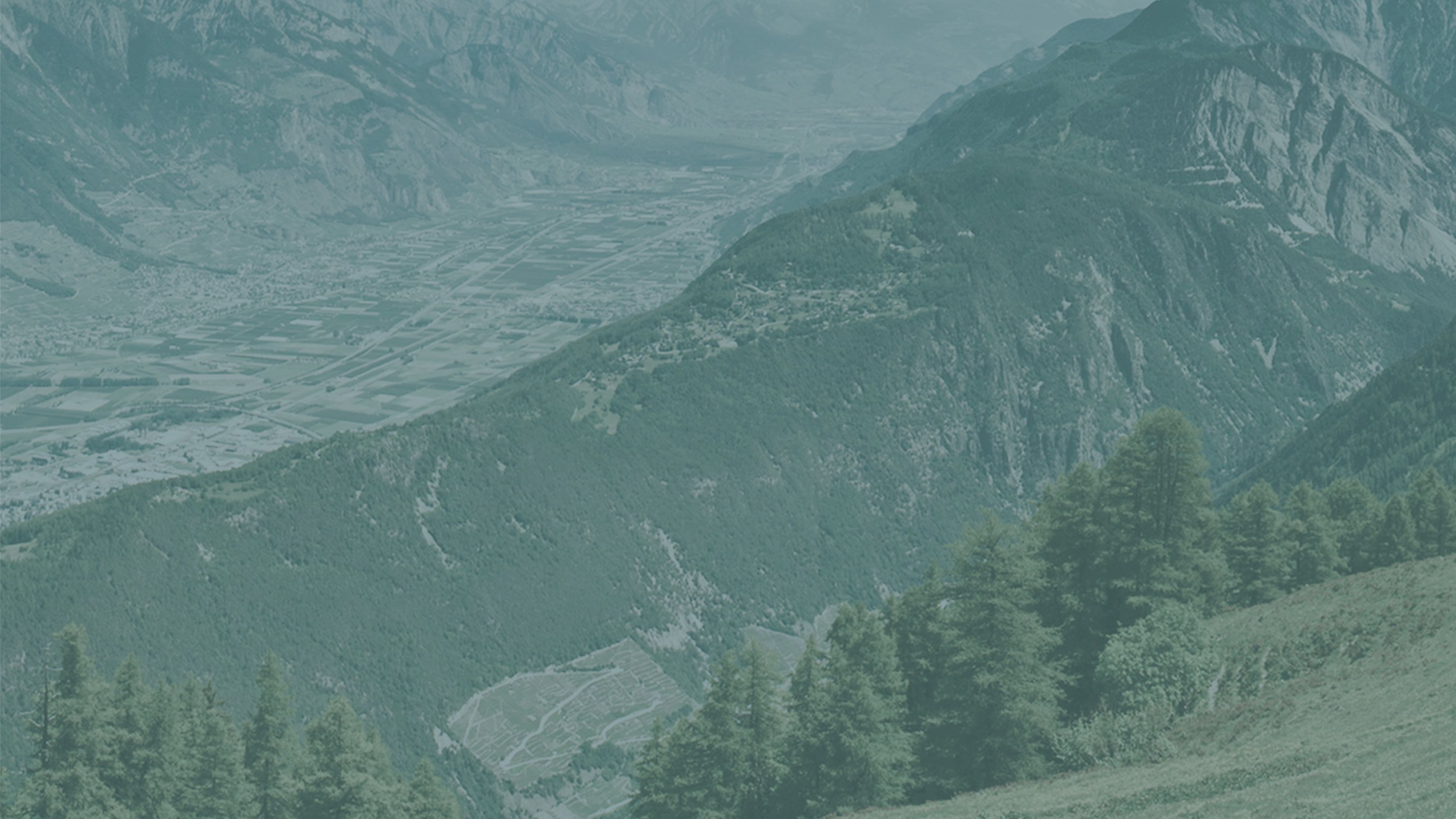 Landscape of the Alps with a town visible behind a mountain ridge