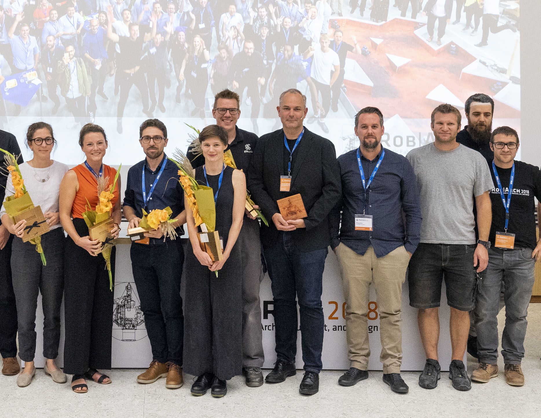Kaitlin McNally holds flowers while standing with other awardees at the Robotic Fabrication in Architecture, Art and Design Conference