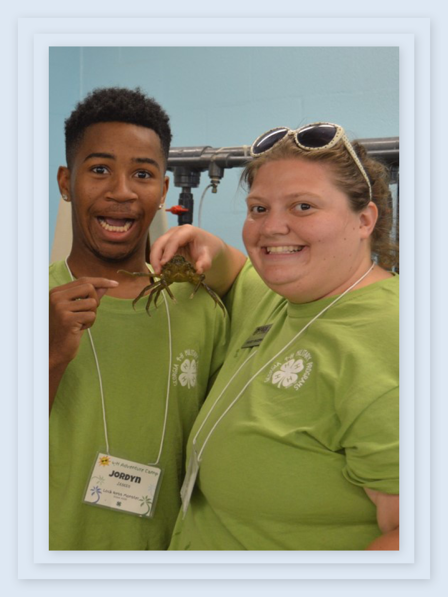 Kasey Bozeman holds a large spider between she and a young student, who points to the spider and makes an alarmed face for the camera.