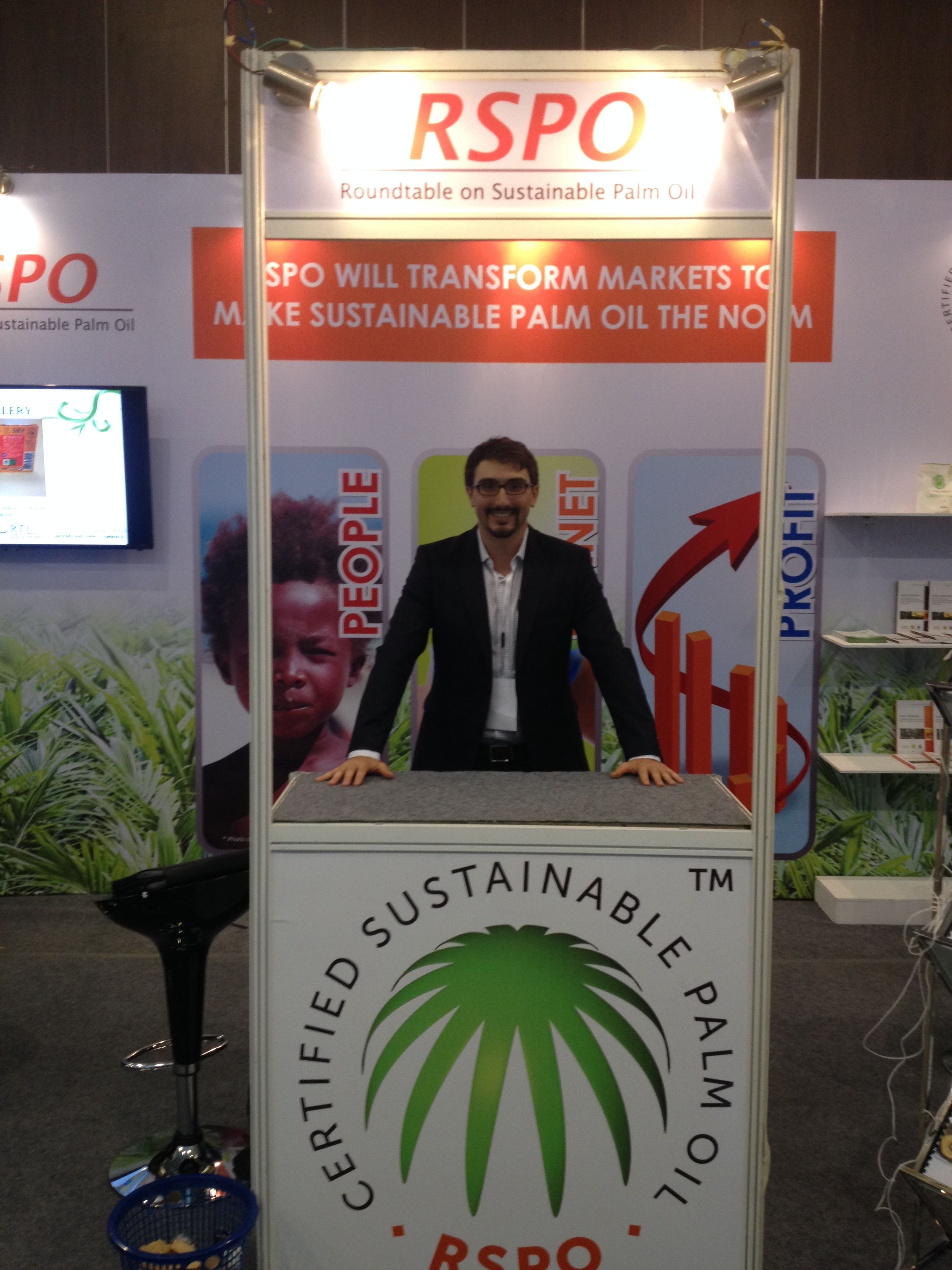 Lee Gross stands at a booth that reads "Certified Sustainable Palm Oil" during a sustainable palm oil conference.