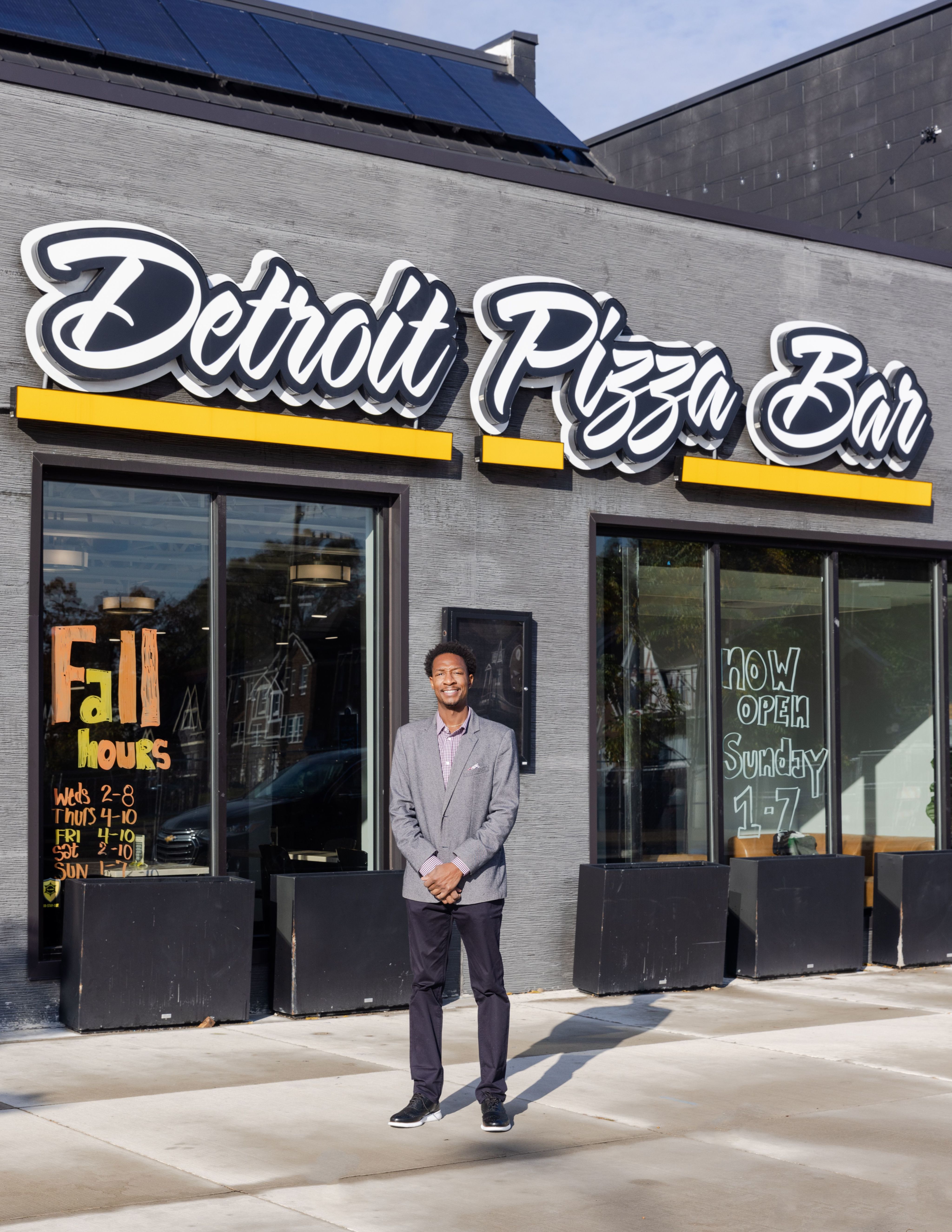 Marcus Jones smiling in front of his restaurant, Detroit Pizza Bar.