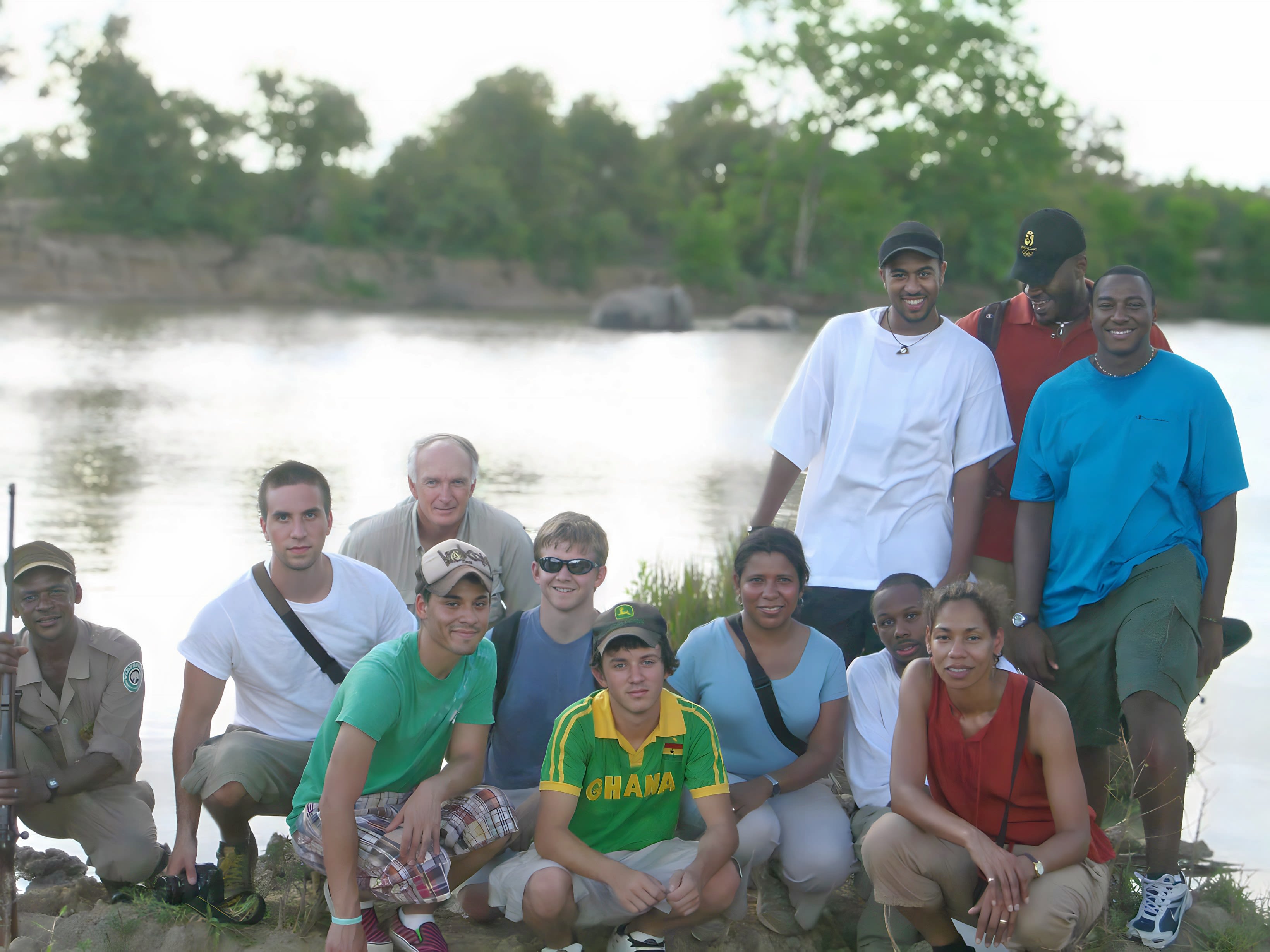 A group of people stand and kneel along a river bank. Walcott is standing with students on the far right.