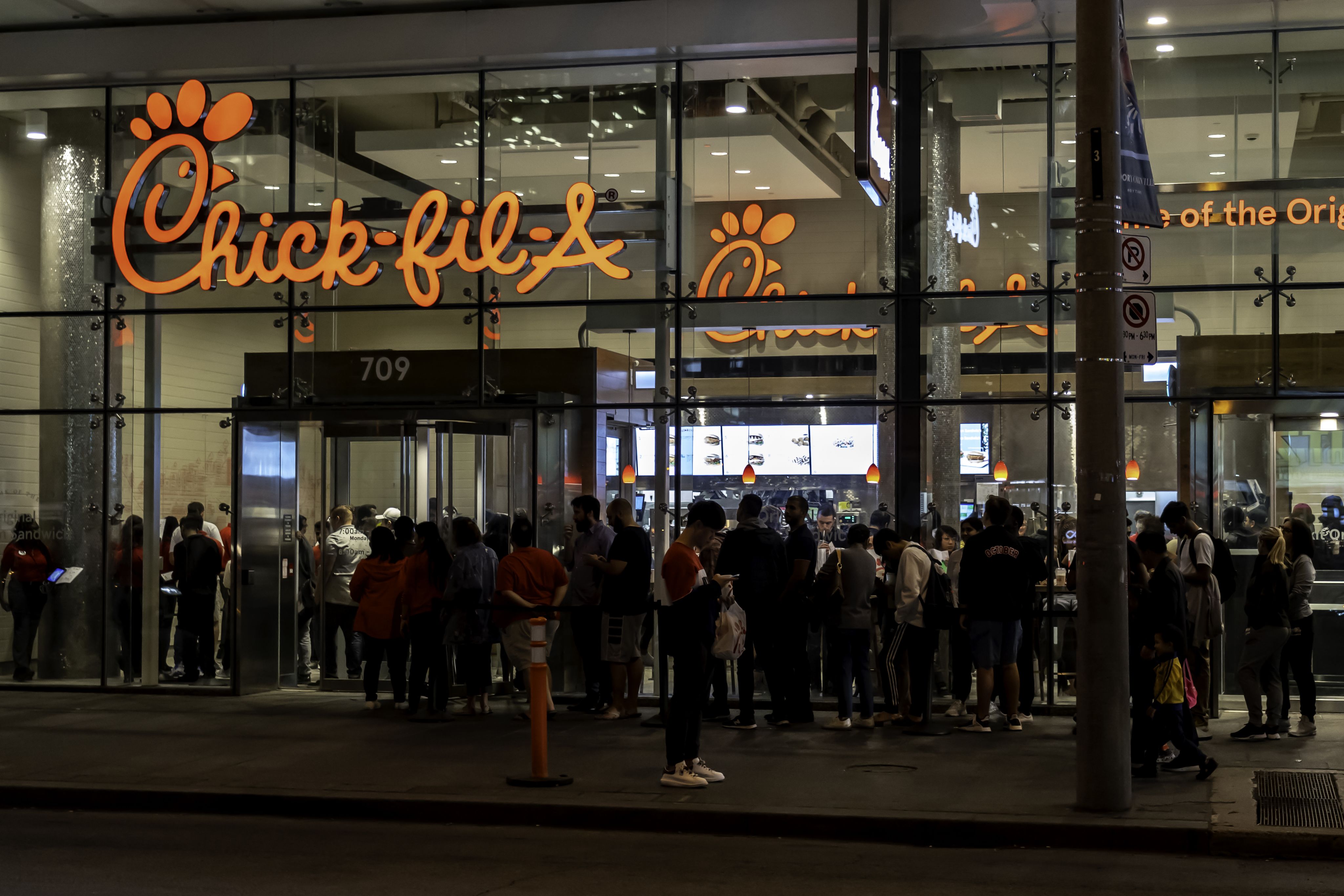 A line forms outside of a Chick-fil-A in Toronto, Canada, at night